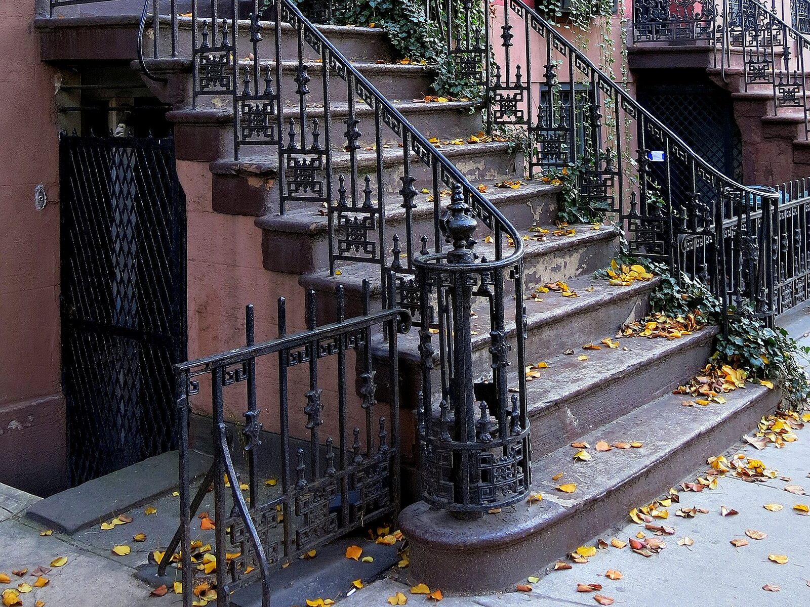 Echtes Foto: Hauseingang mit schmiedeeisernem Geländer und Herbstlaub in der Perry Street im Greenwich Village, New York