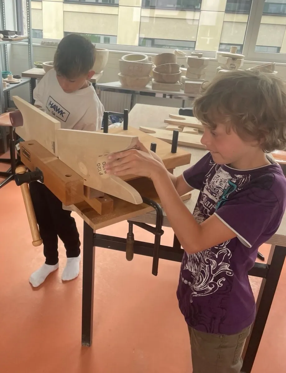 Kinder arbeiten mit Holz an einer Werkbank.